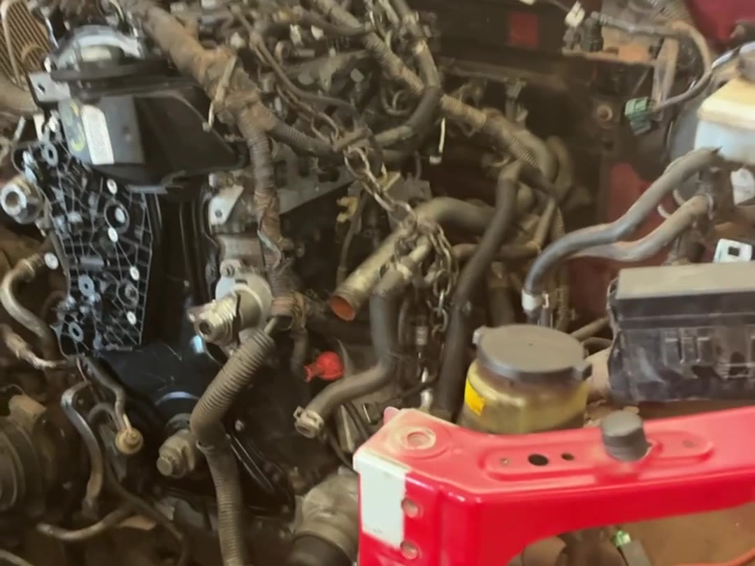 Motor de uma Nissan Frontier sendo içado por talha na oficina