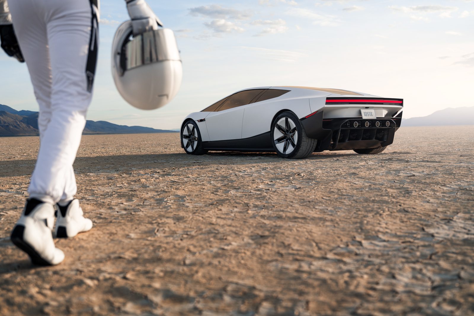 Novo Tesla Roadster branco parado num deserto, com um piloto de macacão caminhando em direção ao carro